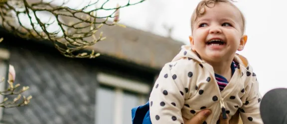 Lachendes Kleinkind wird auf Händen getragen