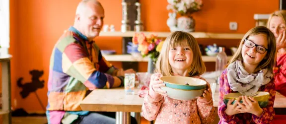 Zwei Mädchen mit Schüsseln vor einem Esstisch in einer Familienwohngruppe