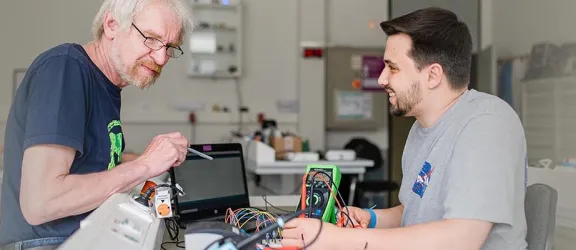 Ausbilder und Azubi probieren etwas in der Elektroabteilung aus