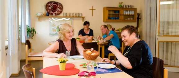 Zwei Menschen sitzen an einem Tisch der Förderstätte und essen