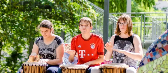 Drei Kinder und ein Lehrer der Berufsschulstufe der Comenius Schule trommeln