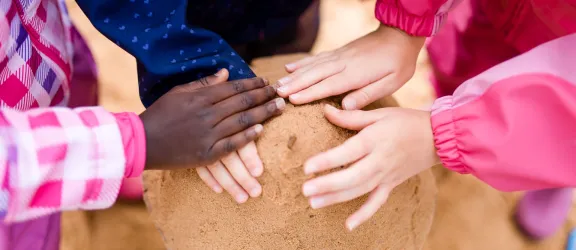 Kindergartenkinder bauen zusammen einen Sandturm