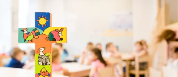 Bemaltes Holzkreuz auf dem Tisch im Kindergarten