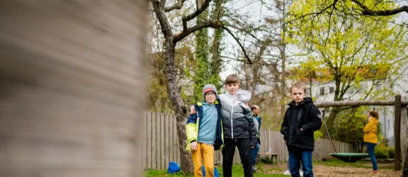 Drei Jungs stehen im Garten der Heilpädagogischen Tagesstätte der Rummelsberger Diakonie