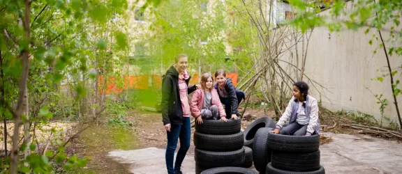 Drei Kinder turnen auf Autoreifen im Garten der Kindertagesstätte