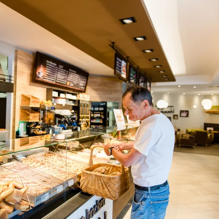 Ein Mann steht an der Theke einer Bäckerei und kauft ein