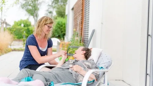 Eine Frau liegt im Liegestuhl auf der Terrasse eine andere Frau sitzt daneben