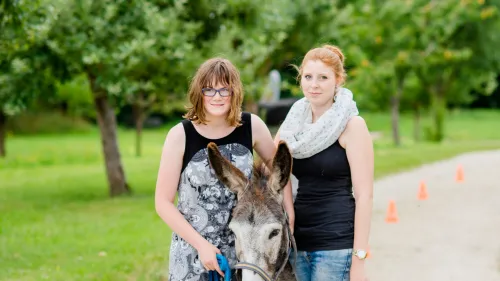 Zwei Frauen spazieren mit einem Esel